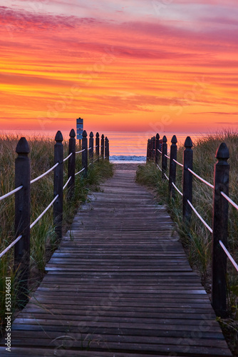 Tablou canvas Orange and red sunrise light with straight boardwalk path guiding you to beach