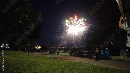 Colorful Fireworks Display With Woman Standing Up Taking Video Footage On Her Cellphone photo