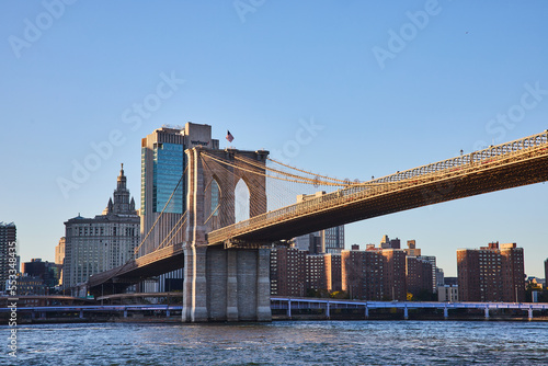 Brooklyn Bridge in New York City with city skyline in background along river
