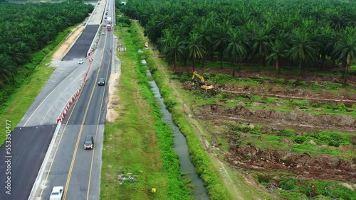 Aerial drone fly around sabrang estate sime darby plantation, thriving palm tree farm in teluk intan along side E32 west coast expressway, interstate highway, excavator removing the grove, perak. photo