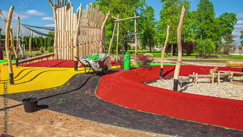 Static shot of a workers constructing colorful rubber flooring in a playground on a sunny day in timelapse. Colorful landscape. photo