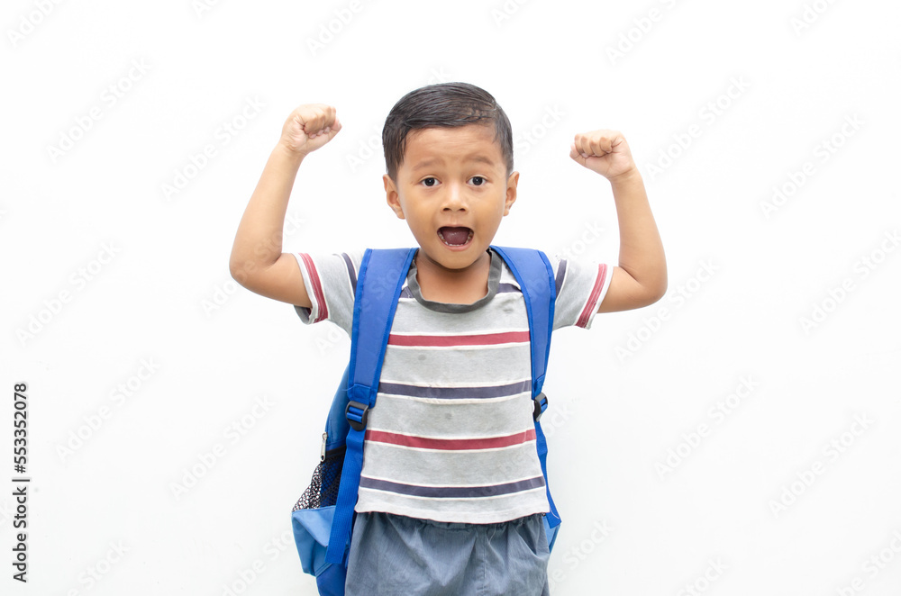A cheerful schoolboy holding a backpack poses alone against a white background. A cheerful schoolboy holding a backpack poses alone against a white background.