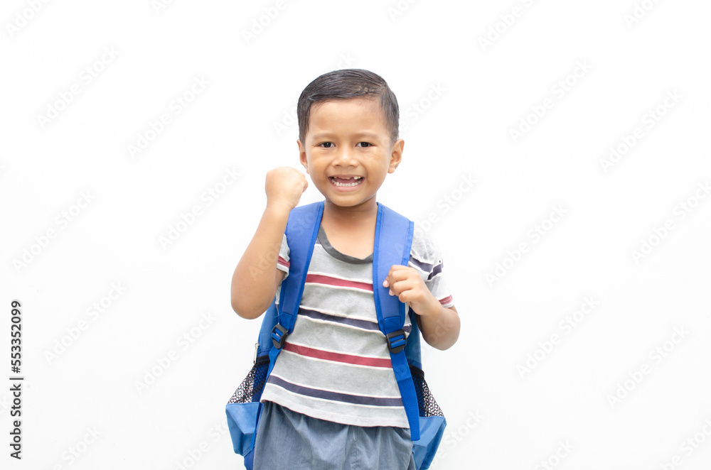 A cheerful schoolboy holding a backpack poses alone against a white background. A cheerful schoolboy holding a backpack poses alone against a white background.