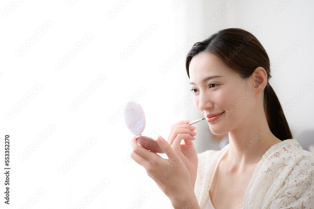 Photo of a beautiful woman putting the finishing touches on her makeup with a lipstick. Photo of a beautiful woman putting the finishing touches on her makeup with a lipstick.