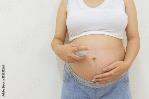 Close up photo of pregnant woman holding a bottle of body lotion © Suksan