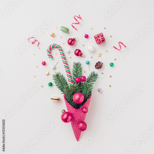 Creative Christmas concept made with New Years decoration baubles in ice cream cone and ornament decoration on white background . Minimal concept of Christmas and New Year holiday style. Flat lay.