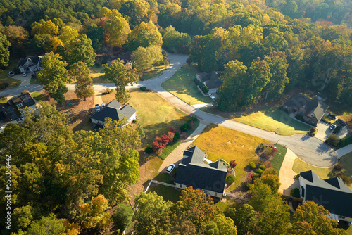 View from above of expensive residential houses between yellow fall trees in suburban area in South Carolina. American dream homes as example of real estate development in US suburbs