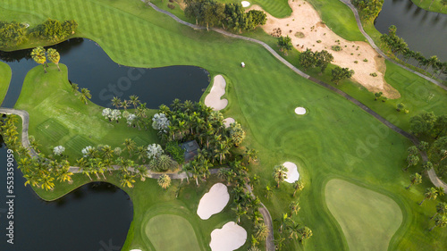 Aerial view of green golf course and putting green, Aerial view of green grass and coconut palm trees on gree golf field, fairway, sand bunker and putting green.