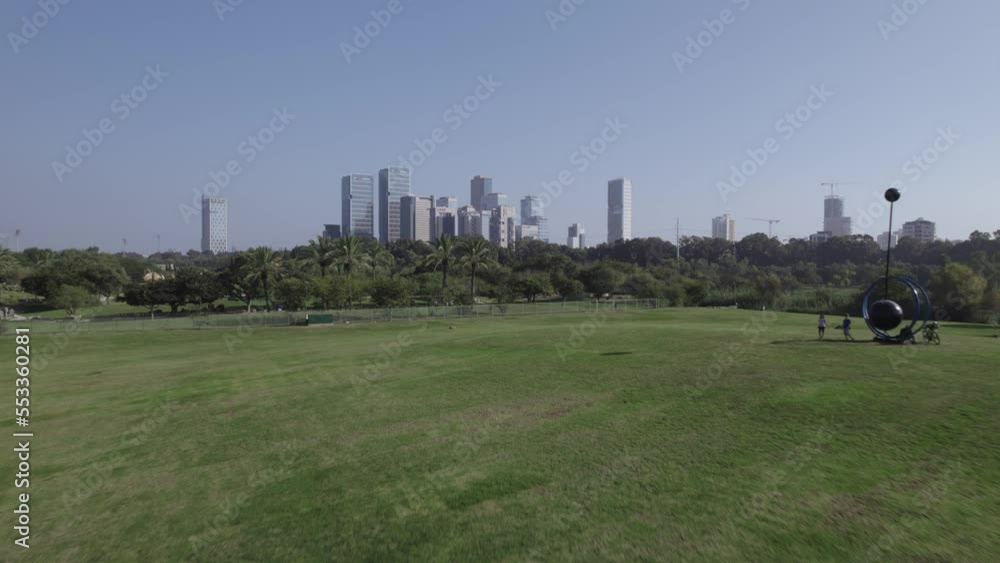 Fast aerial shoot over huge grassy field with office buildings in the background - Yarkon Park #005 Fast aerial shoot over huge grassy field with office buildings in the background - Yarkon Park #005