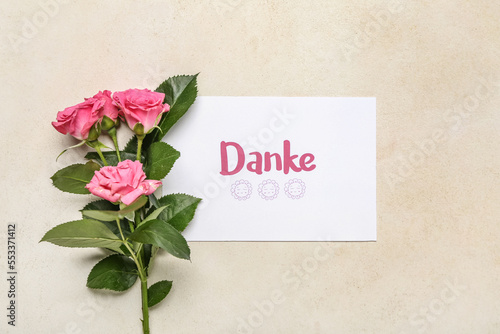 Card with text DANKE and rose flowers on light background