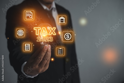 Man holding a light bulb. Tax letters. Tax word on business background and tax concept 2023 tax payment, new 2023 tax concept.