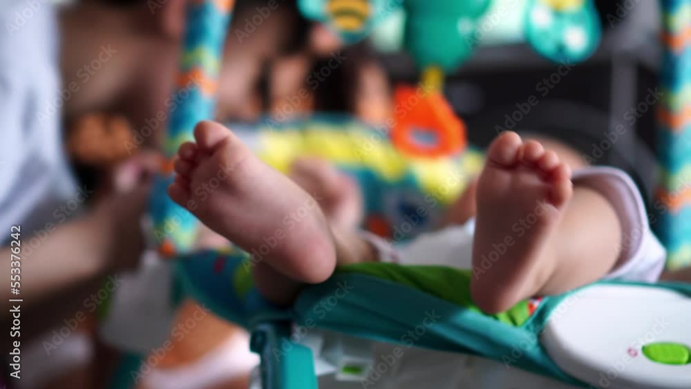 Close up leg of baby at cradle. Background is sister and brother interact Close up leg of baby at cradle. Background is sister and brother interact