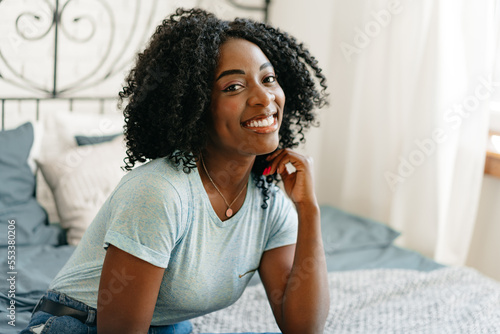 Beautiful young thoughtful african woman sitting in bed