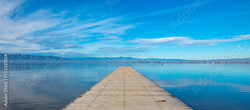 Fototapeta Naklejka Na Ścianę i Meble -  Wooden pier,  beautiful blue lake and clouds reflection ( Delta del Ebro,  Spain)
