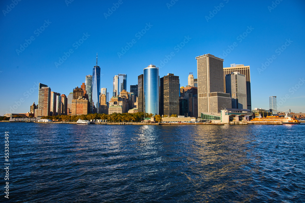 Fototapeta premium Beautiful New York City skyline from the water with sunlight hitting southern Manhattan