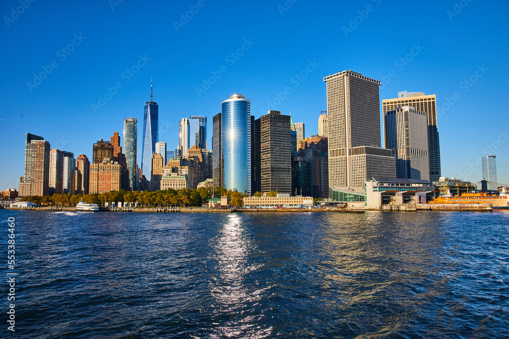 Obraz premium Stunning New York City skyline from boat with sun shining over skyscrapers