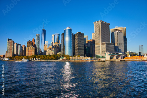 Stunning New York City skyline from boat with sun shining over skyscrapers © Nicholas J. Klein