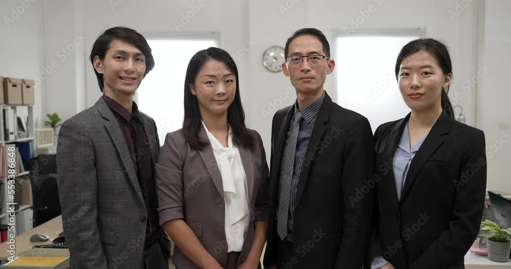 portrait shot of smiling business team of four standing and smiling at camera against a modern bright office background portrait shot of smiling business team of four standing and smiling at camera against a modern bright office background