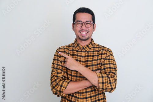 Adult Asian man smiling confident at camera while pointing to the right side