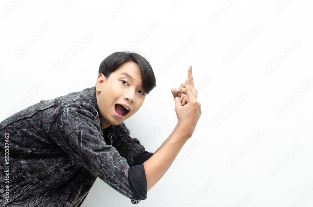 Happy Ecstatic asian man wear jeans jacket pointing finger to copy space presenting and showing goods. billboard model advertisment concept. man with wow face showing something. Happy Ecstatic asian man wear jeans jacket pointing finger to copy space presenting and showing goods. billboard model advertisment concept. man with wow face showing something.