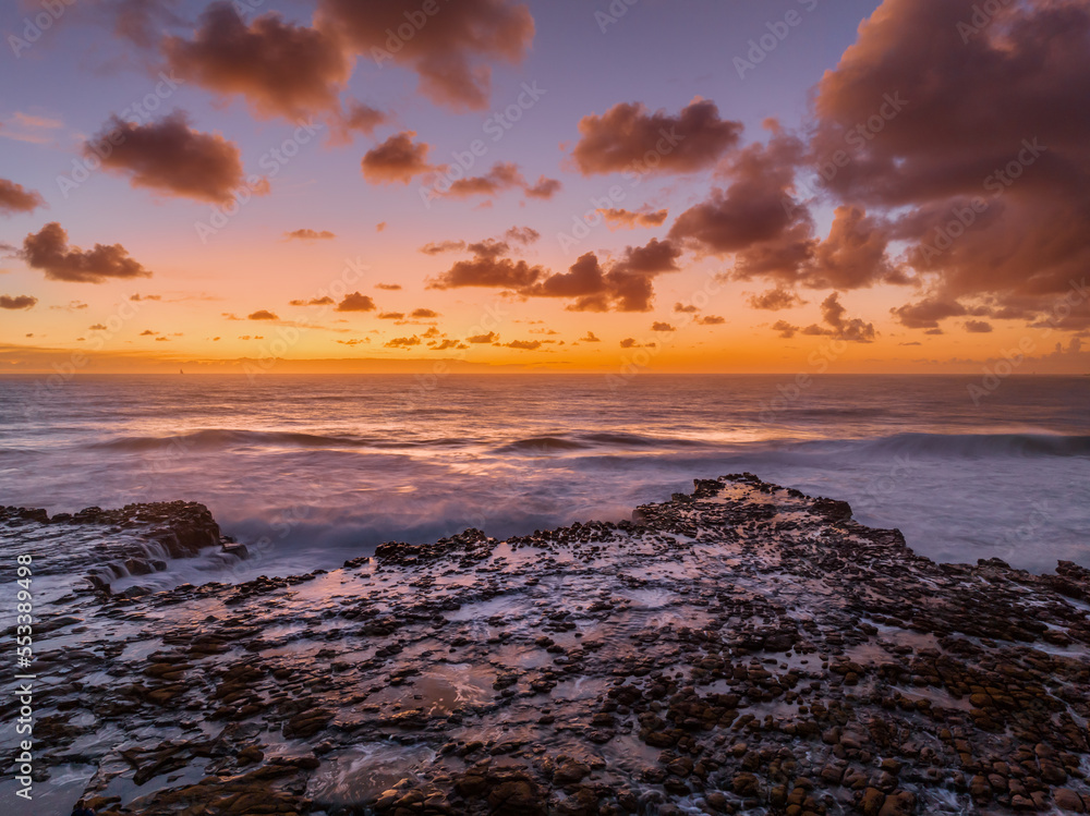 Surfs up sunrise at the seaside with scattered clouds