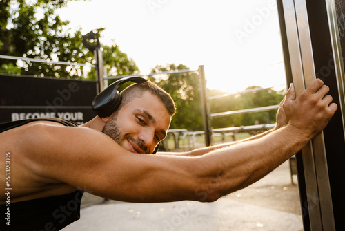 Young smiling man athlete doing workout outdoors