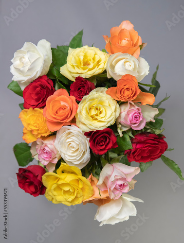 beautiful bouquet of white roses with pink ribbons and green leaves on a light background 