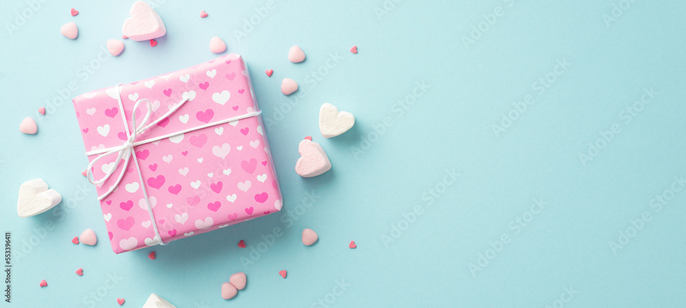 Valentine's Day concept. Top view photo of pink giftbox heart shaped marshmallow and sprinkles on isolated pastel blue background with empty space Valentine's Day concept. Top view photo of pink giftbox heart shaped marshmallow and sprinkles on isolated pastel blue background with empty space