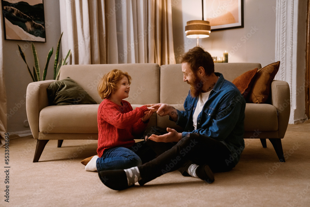 Happy father and son having fun together while sitting on floor Happy father and son having fun together while sitting on floor