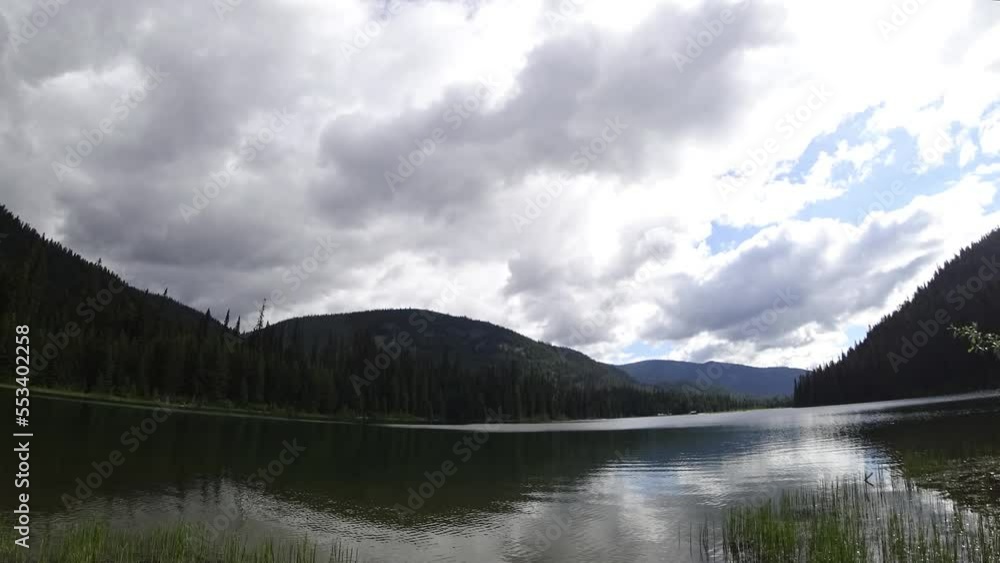 Timelapse of lake with mountains around, fast moving clouds in Canada