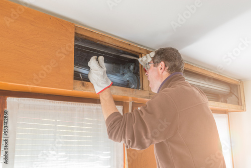 Broken house roller shutter. Man agape and surprised by the damage who requires the call of a specialized repairer. Concept of repairing or replacing a roller shutter with a more modern one
