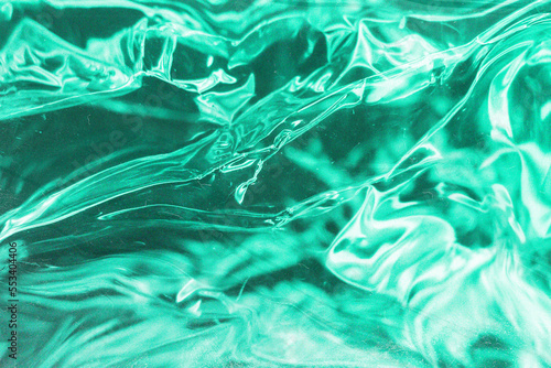 Green holographic glitter background plastic surface texture. Abstract green glowing polyethylene. Green holographic wallpaper