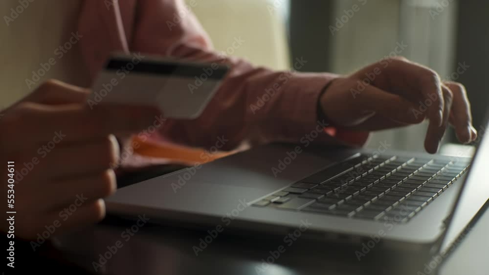 Close-up cropped shot of unrecognizable man with credit card in hands making purchases online, using laptop computer for making online transaction, input data for paying online, slow motion. Close-up cropped shot of unrecognizable man with credit card in hands making purchases online, using laptop computer for making online transaction, input data for paying online, slow motion.