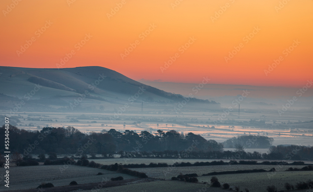 Misty morning December sunrise over mount Caburn from Kingston Ridge on the south downs east Sussex south east England