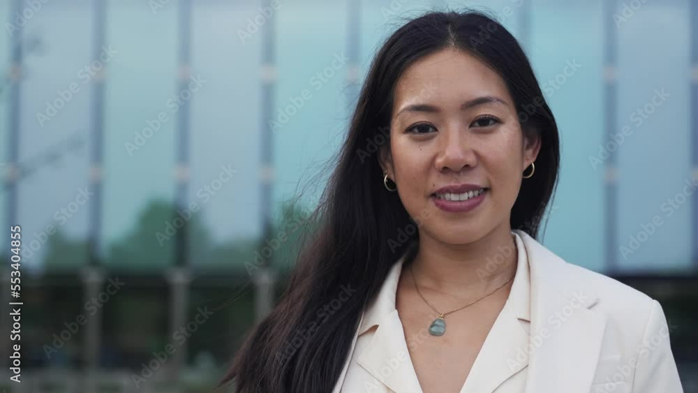 Portrait of young elegant asian business woman standing in front of office glass windows, positive and smiling Portrait of young elegant asian business woman standing in front of office glass windows, positive and smiling
