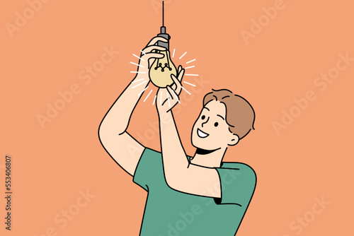 Smiling young man screwing lightbulb at home. Happy guy connect light bulb for light indoors. Vector illustration. 