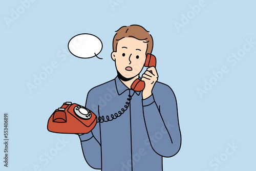 Stunned young man talking on landline phone. Amazed male with speech bubble above head speak on wired headset. Vector illustration. 