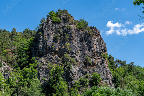 rocher avec sa falaise a pic recouvert d'arbres verts proche de Courgoul dans le puy de dôme par une belle journée d'été