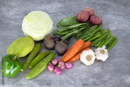 Fototapeta Naklejka Na Ścianę i Meble -  Organic fresh vegetables in isolated background. Close up view of fresh organic vegetables cabage, carrot, big red onions, small red onions, cucumbers, bell pepper - capsicum , beetroots , beans
