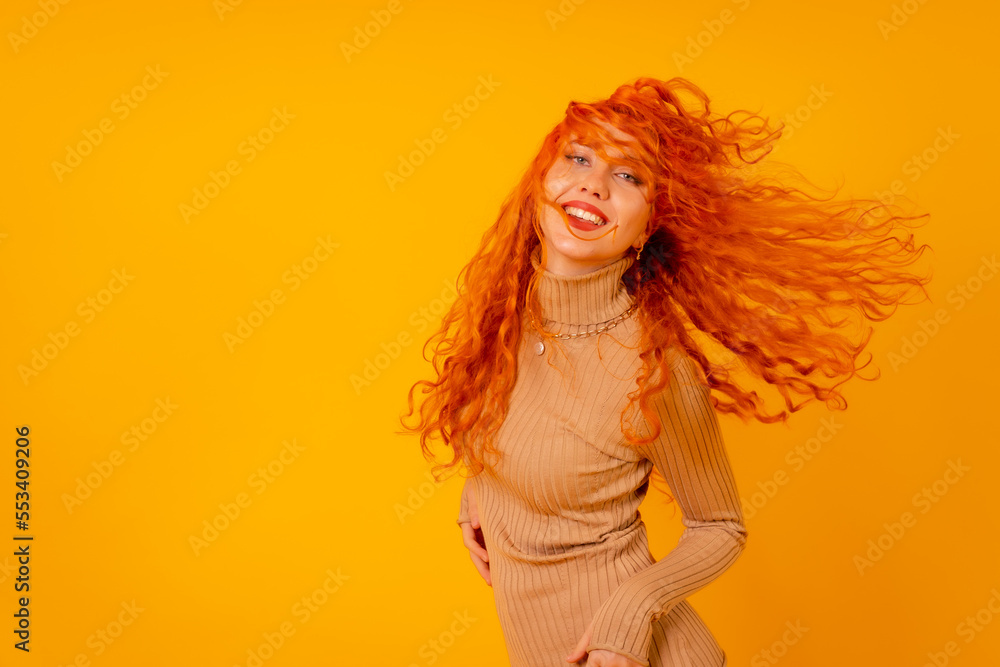Red-haired woman on a yellow background, studio shot, moving her hair and with frozen hair Red-haired woman on a yellow background, studio shot, moving her hair and with frozen hair