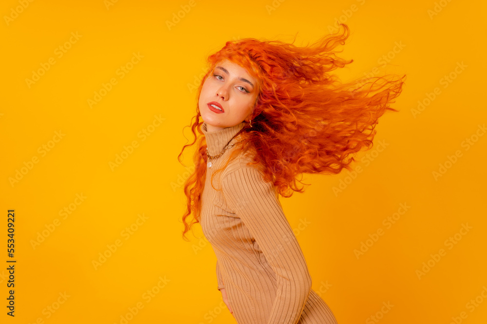Red-haired woman on a yellow background, studio shot, moving her hair and with frozen hair Red-haired woman on a yellow background, studio shot, moving her hair and with frozen hair