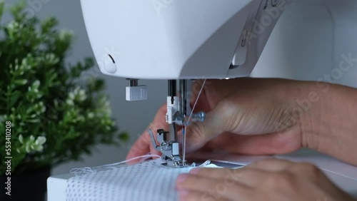 Woman hands sewing at a sewing machine. Designer sitting and sewing. Dressmaker working on the sewing machine. Concept of clothing production. Home production.Handmade. Close up view of hands. High qu