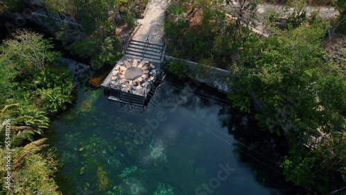 People doing yoga above the water surrounded by trees at MAYAN CENOTE in RIVIERA MAYA photo