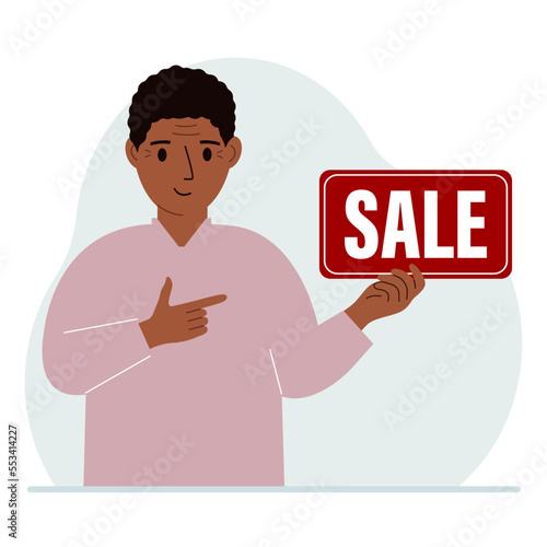 A man holds a banner with the text sale. Points a finger at the text. The concept of a discount, a special offer in a store or a bank, an advertising flyer.