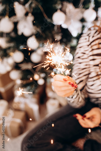 Fototapeta Naklejka Na Ścianę i Meble -  Bengal fire in a female hand, holiday atmosphere, New Year's decorations 