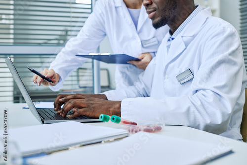 Close up of scientist using laptop while doing research in medical lab, copy space
