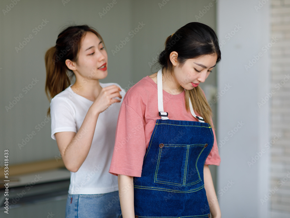 Millennial two Asian young beautiful female florist helping wearing jeans apron standing smiling in floral shop Millennial two Asian young beautiful female florist helping wearing jeans apron standing smiling in floral shop