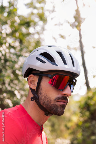 portrait of a young man wearing a helmet and cycling goggles in the middle of the forest, concept of freedom and sport in nature, copy space for text © Raul Mellado