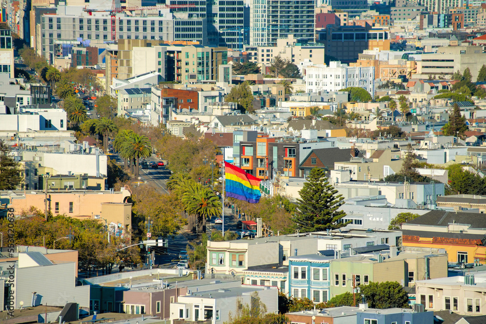 Pride flag in a downtown neighborhood in San Francisco California in midday cityscape with buildings and houses
