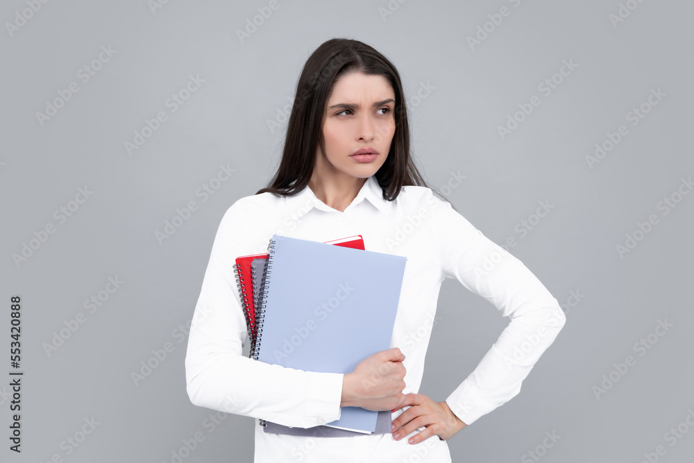 Portrait of student woman. College or high school ducation. Serious woman with notebooks smiling at camera on gray studio background. Young female university student. Portrait of student woman. College or high school ducation. Serious woman with notebooks smiling at camera on gray studio background. Young female university student.